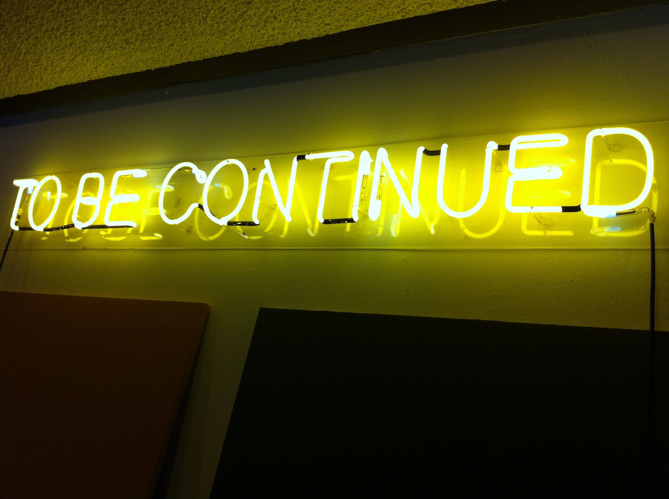 螢光黃 桌布 壁紙 — 一個發光的黃色霓虹燈牌，上面寫著「TO BE CONTINUED」，背景是光線昏暗的紋理牆壁。