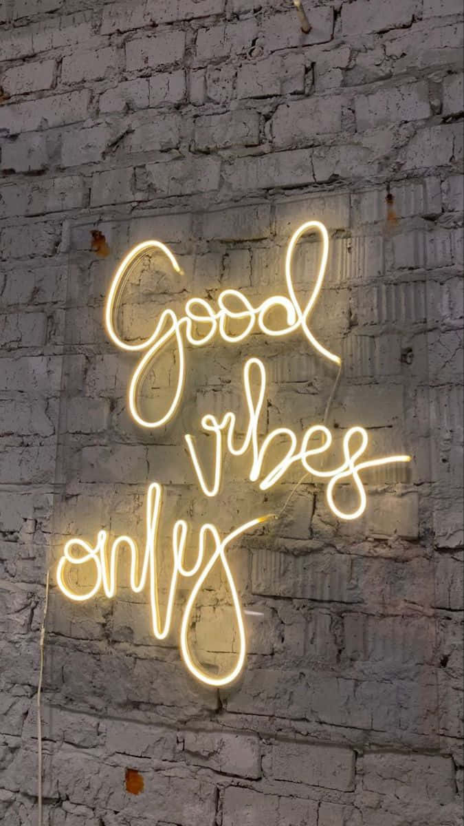 語錄 桌布 壁紙 — 一個發光的黃色霓虹燈牌，以草書寫著「Good vibes only」，背景是帶紋理的白色磚牆。
