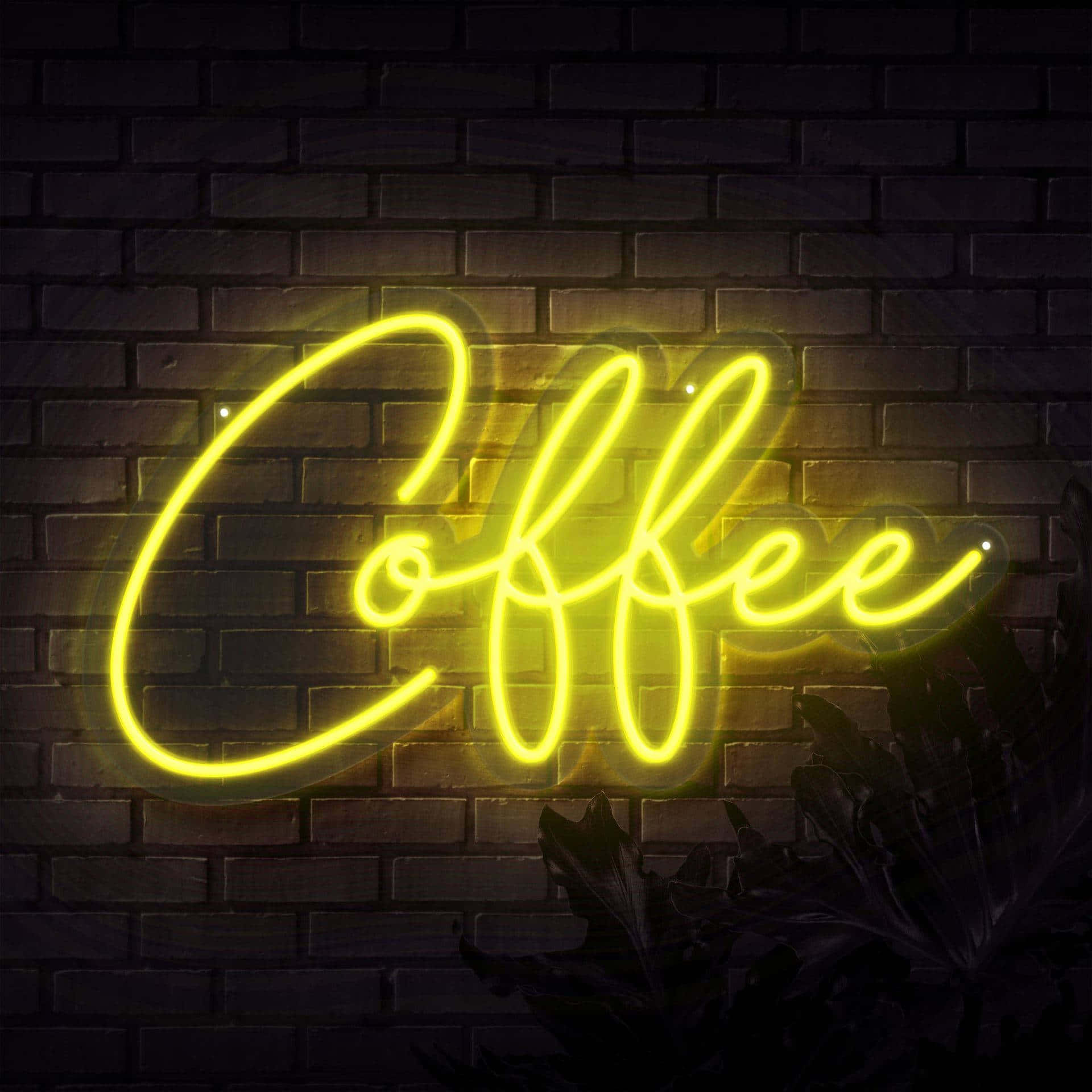 桌布 壁紙 — 一個發光的黃色霓虹燈牌，拼寫著 'Coffee'，在夜晚照亮了深色的磚牆，柔和的光線在下方的葉子上投下陰影。