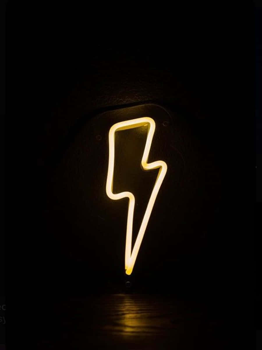 Neon Lightning 桌布 壁紙 — 一個發光的黃色霓虹閃電標誌在黑色牆壁上，在黑暗潮濕的地板上投射出溫暖的倒影。