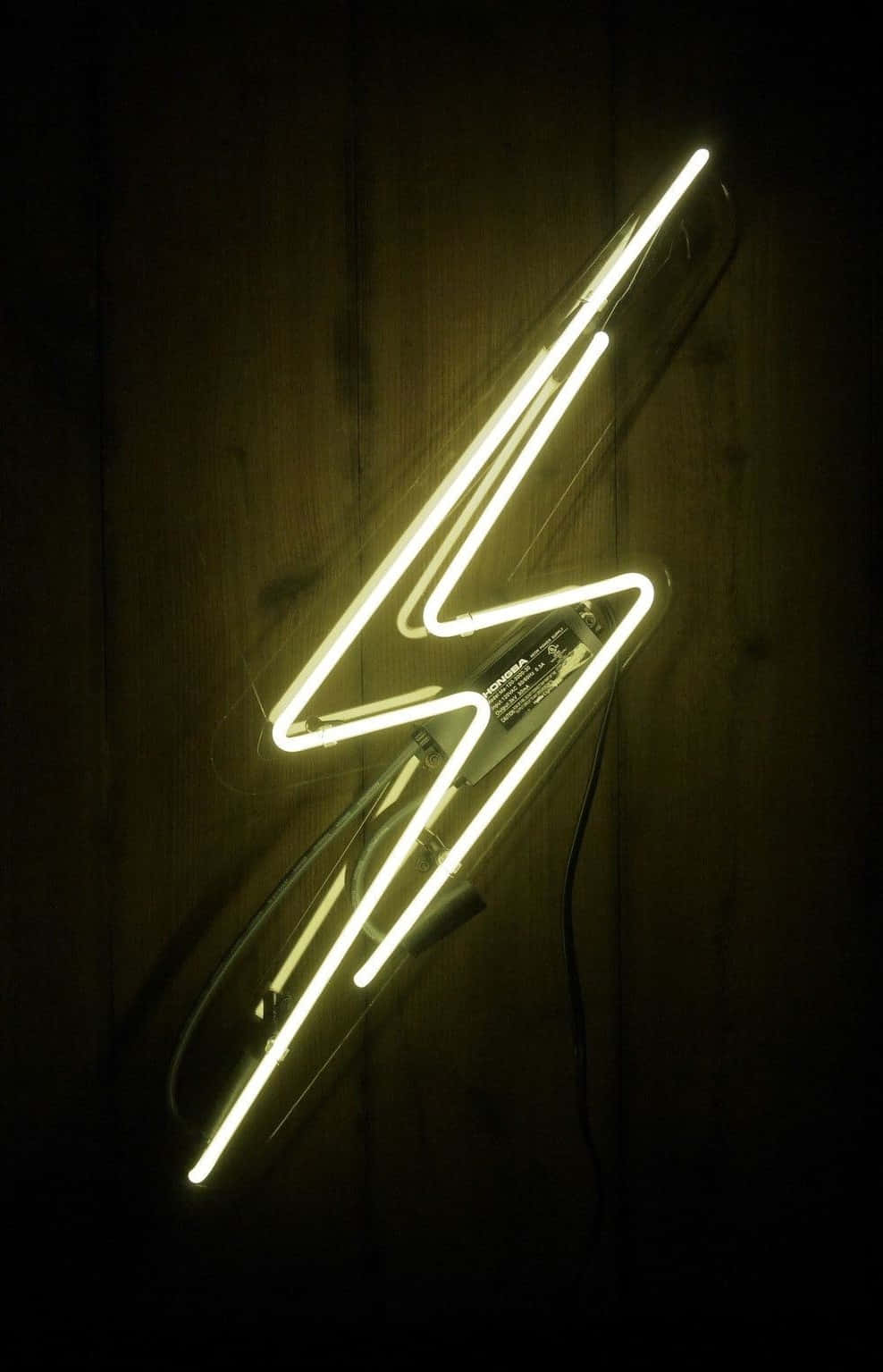 Lightning Bolt iPhone 桌布 壁紙 — 一個發光的黃色霓虹閃電標誌安裝在昏暗房間的深色木牆上。