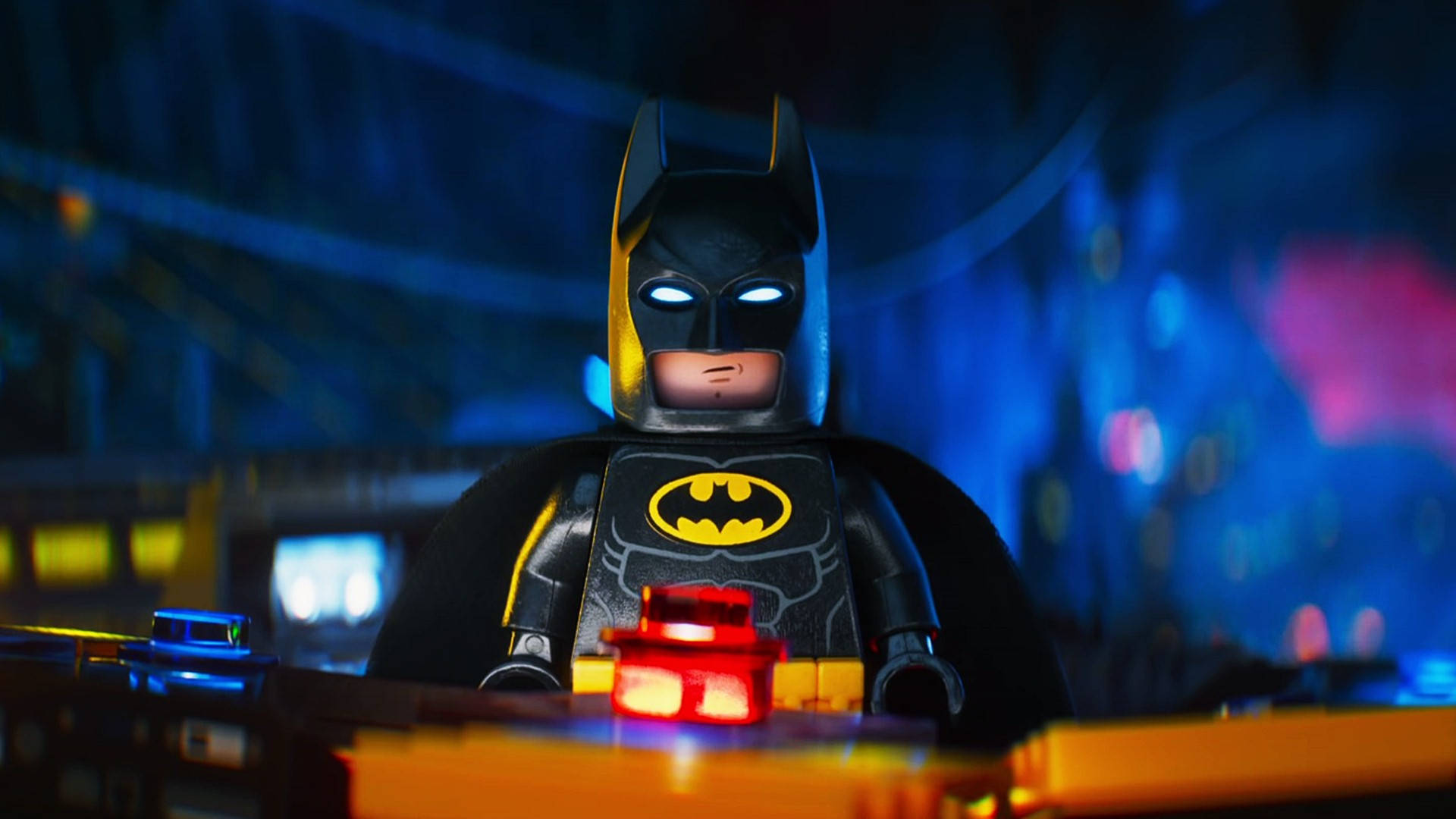 Batman Animated 桌布 壁紙 — 一個發光眼睛的LEGO蝙蝠俠迷你人偶站在夜晚霓虹燈閃爍的高譚市景觀中。