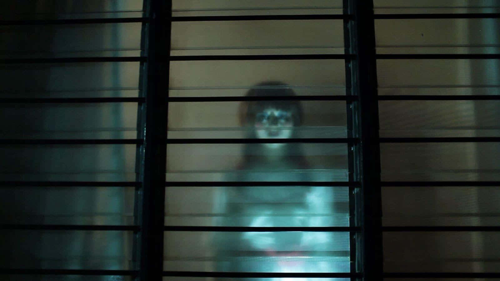 Annabelle 桌布 壁紙 — 一個發光眼睛的鬼影透過昏暗房間的黑色橫向百葉窗窺視。