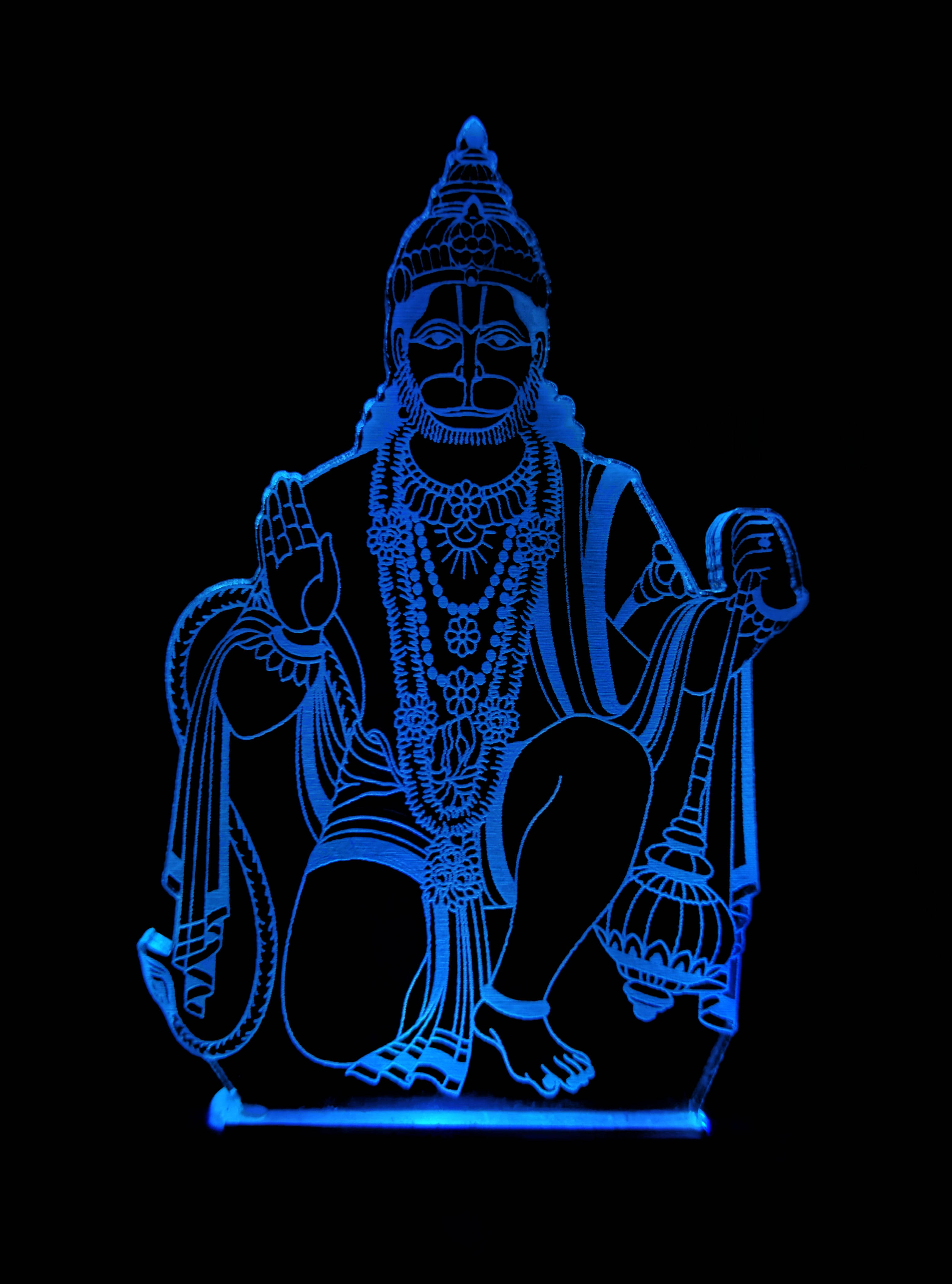 lord hanuman HD 桌布 壁紙 — 一個發光藍色3D幻覺，描繪一位坐著的印度教神祇，飾有精緻珠寶，雙手舉起，背景為黑色。