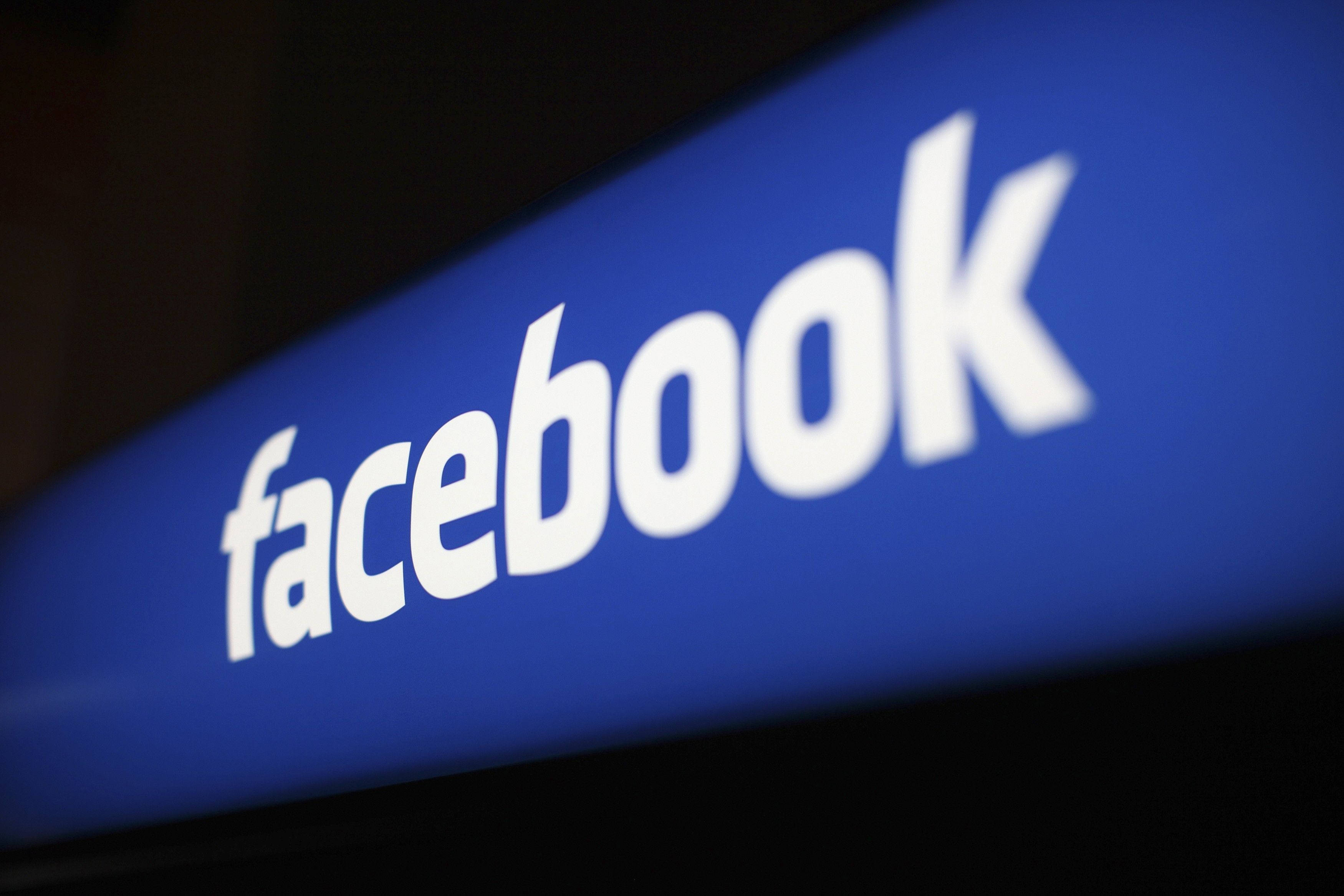 Facebook 桌布 壁紙 — 一個發光藍色Facebook標誌的特寫，帶有白色文字，背景為深色。