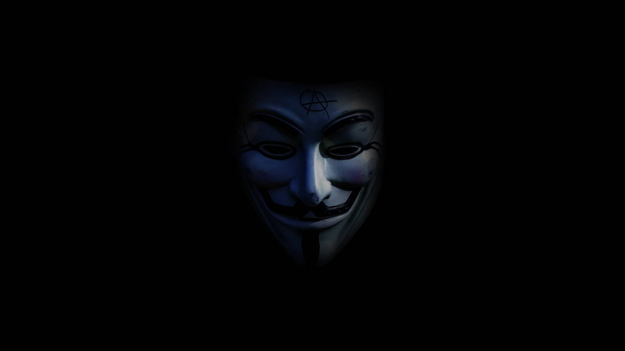 暗色電腦 桌布 壁紙 — 一個白色 Guy Fawkes 面具在黑暗中微弱發光，額頭上有無政府主義符號。