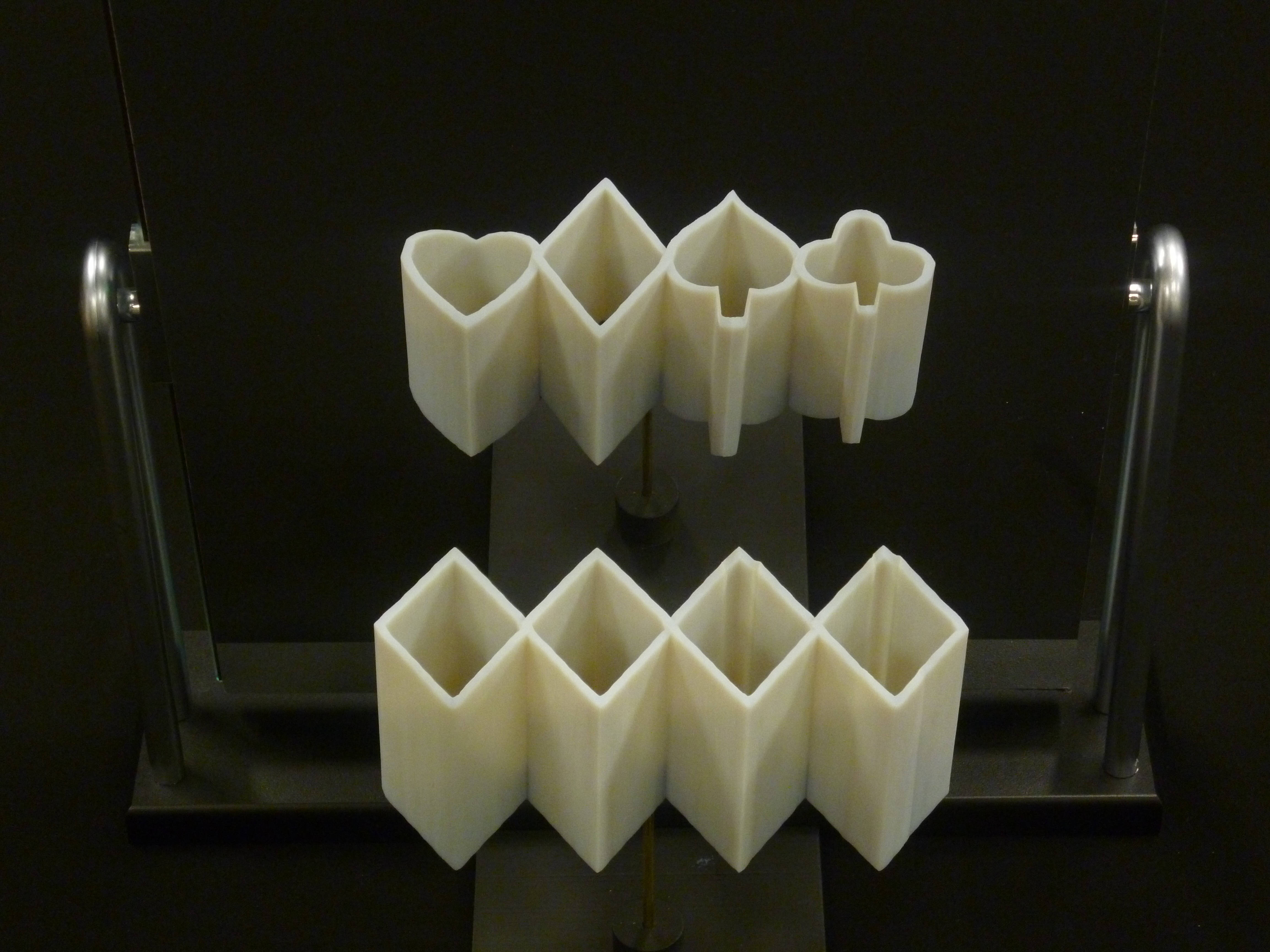 設計 桌布 壁紙 — 一個白色3D列印幾何雕塑，帶有心形和鑽石形狀，展示在黑色底座上，背景為深色。