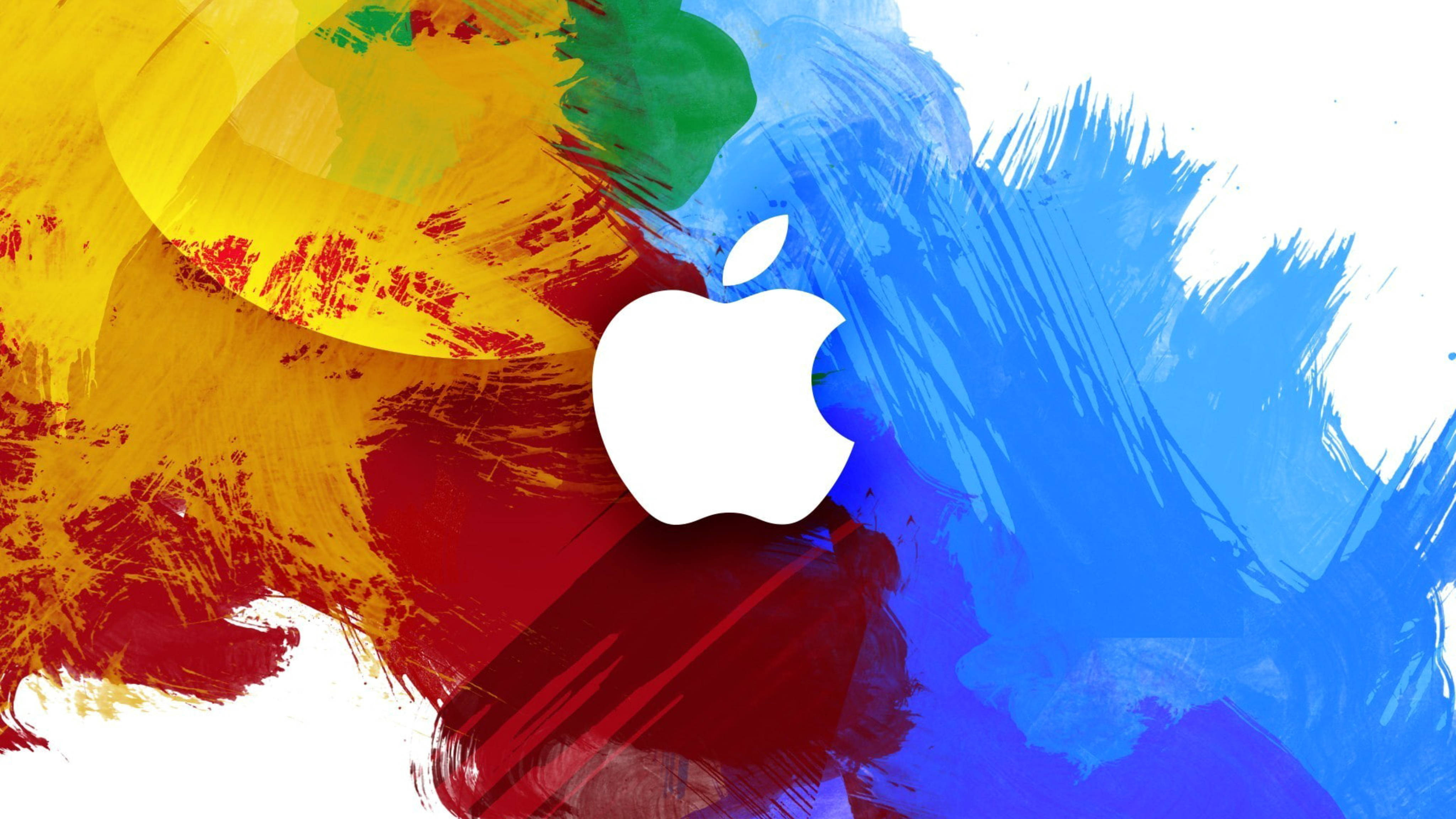 Apple 4K Ultra HD 桌布 壁紙 — 一個白色Apple標誌居中，置於充滿活力的抽象背景上，背景有鮮明的黃色、紅色和藍色油漆筆觸。