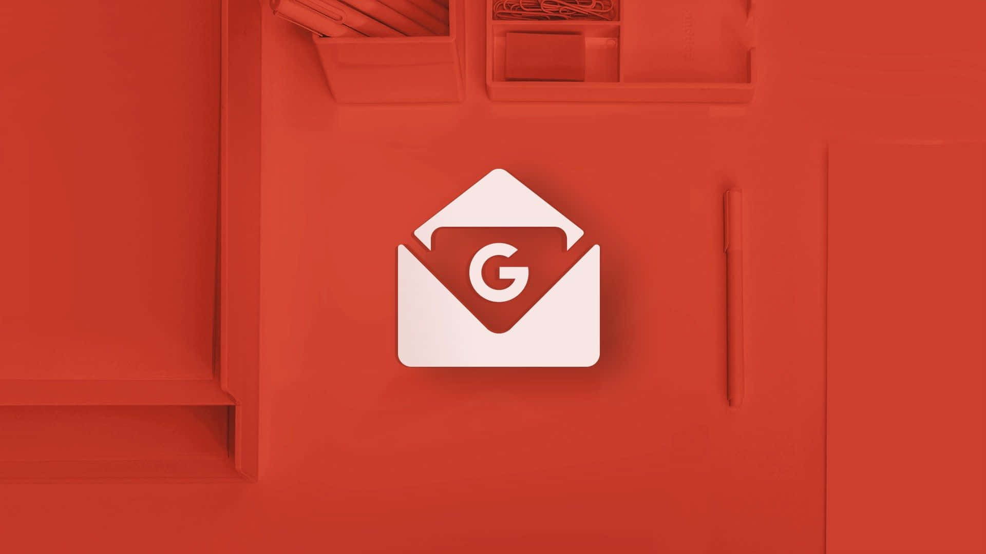 Gmail 動圖 桌布 壁紙 — 一個白色Gmail標誌居中放置在簡約的紅色辦公桌上，辦公用品帶有柔和陰影。