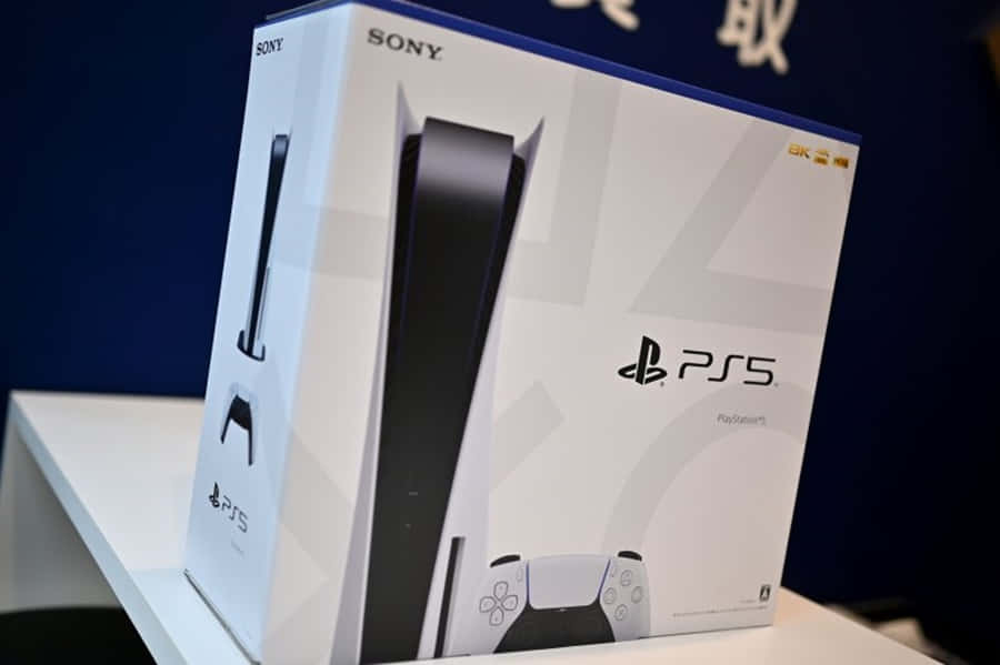 PS5 動態圖片 桌布 壁紙 — 一個白色PlayStation 5主機盒，帶有黑色點綴和控制器圖案，放置在白色層架上，背景為深藍色。