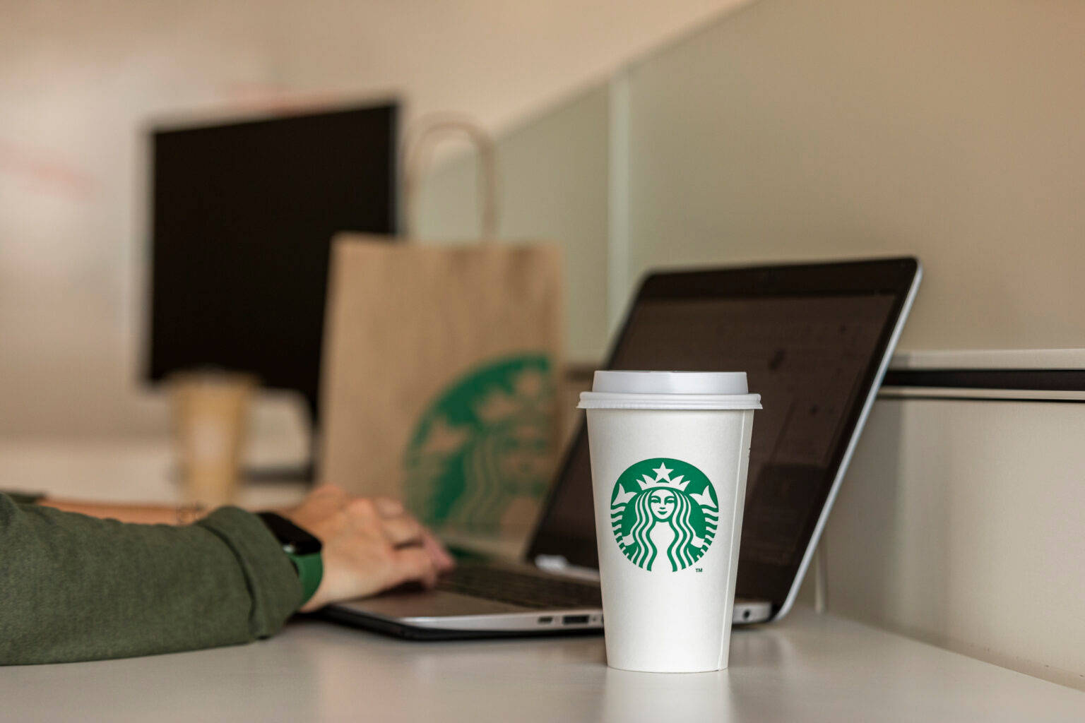 桌上一個Starbucks咖啡杯，旁邊有筆記型電腦，一個人在打字。 — 星巴克 GIF 壁紙