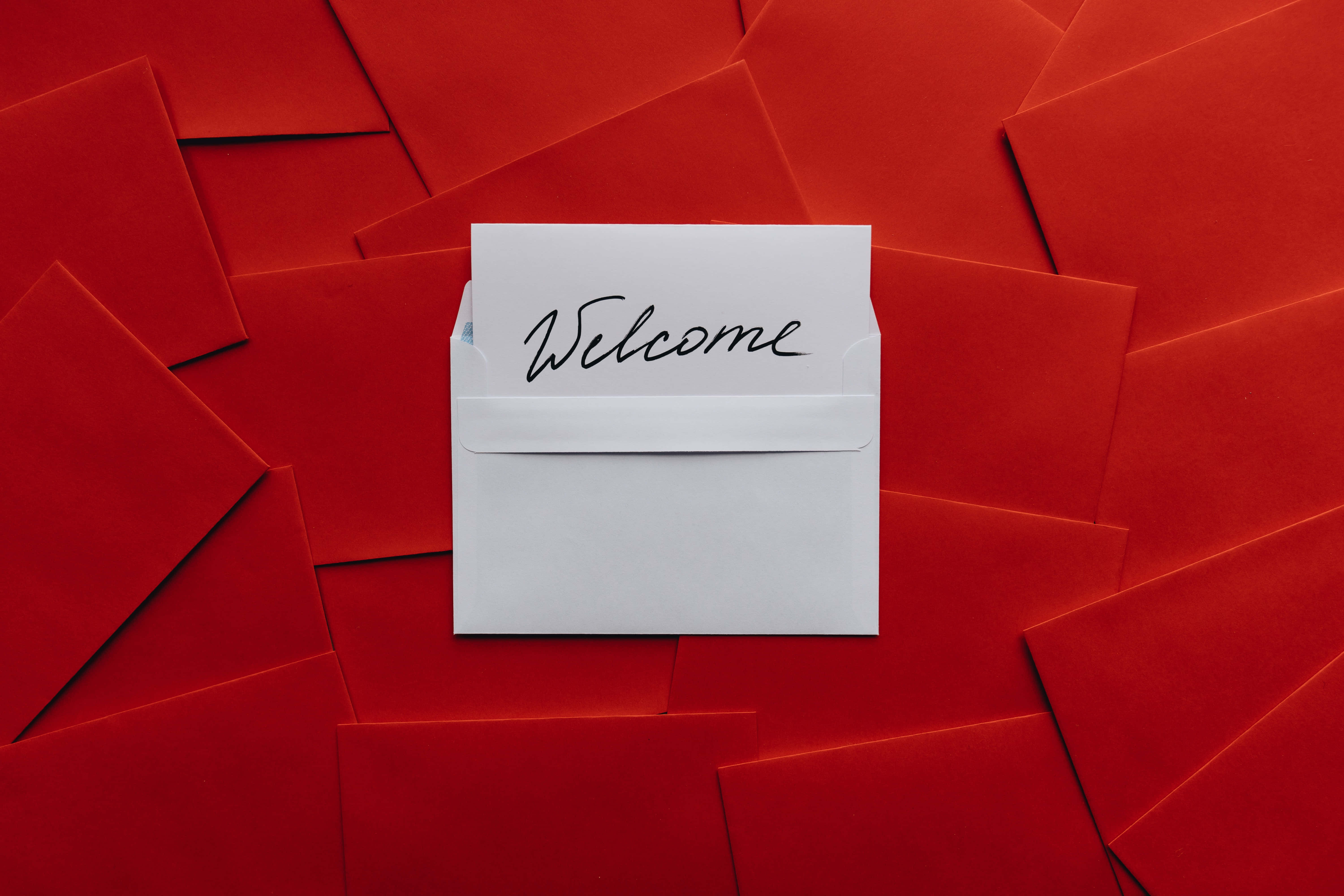 Welcome 桌布 壁紙 — 一個白色信封，內有手寫的歡迎便條，在鮮紅色的信封背景上格外突出。