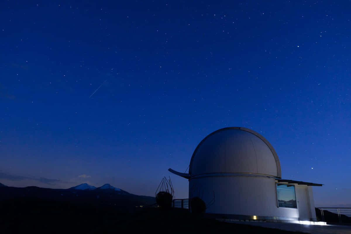 Observatory 桌布 壁紙 — 一個白色天文台圓頂在繁星點點的暮色天空下呈現剪影，遠方有積雪的山脈。