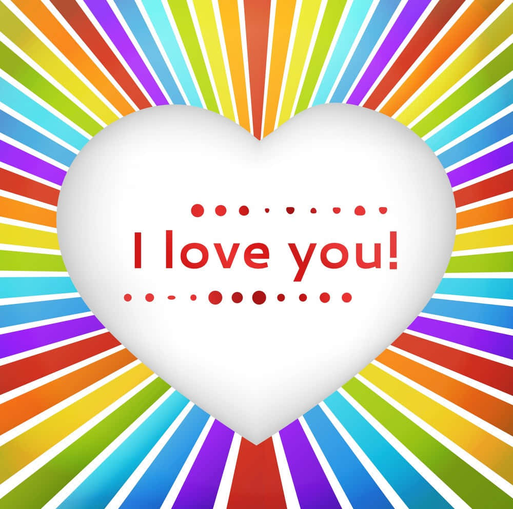 Rainbow Heart 桌布 壁紙 — 一個白色心形，上面有紅色文字寫著「我愛你！」，散發出色彩繽紛的彩虹條紋，呈現歡樂的數位設計。
