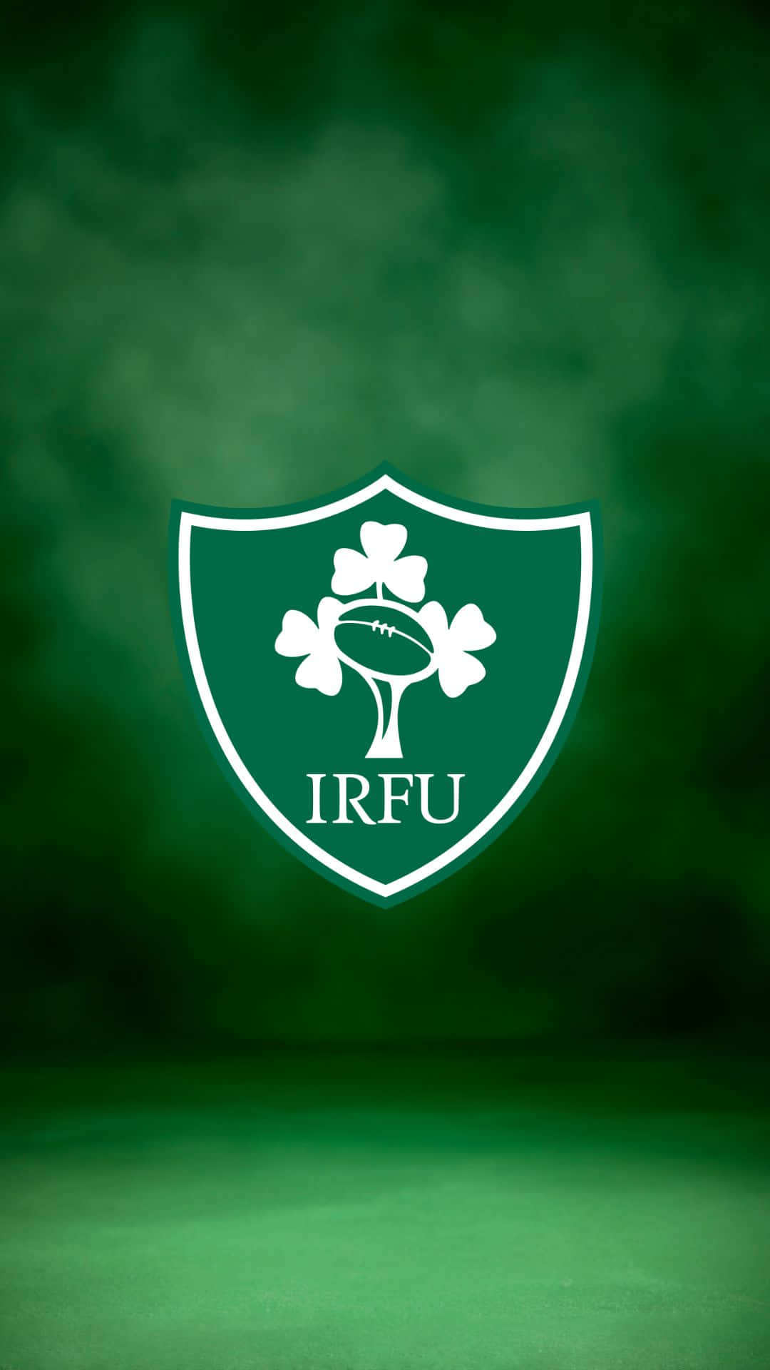 Ireland Rugby 桌布 壁紙 — 一個白色愛爾蘭橄欖球聯盟徽章，中央有三葉草和一個橄欖球，置於漸變綠色背景上。
