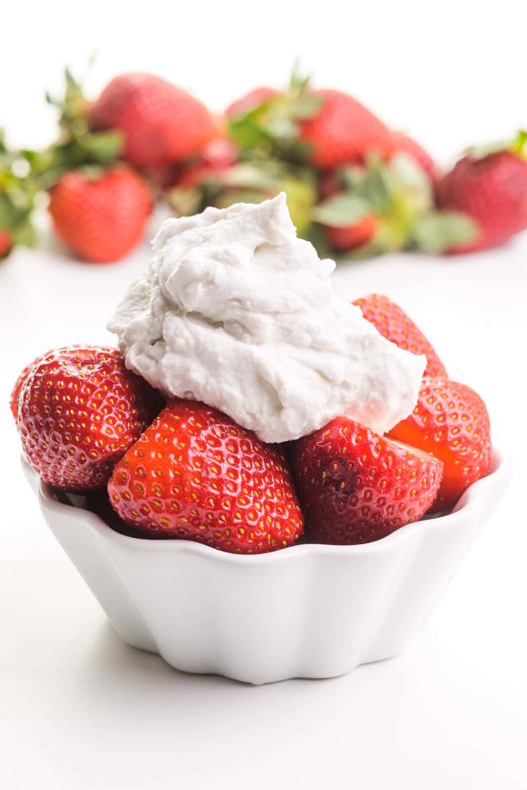 Strawberries 桌布 壁紙 — 一個白色扇貝邊碗盛載著鮮紅色的草莓，上面加上一大團鬆軟的白色鮮奶油，襯托在潔白的背景上。