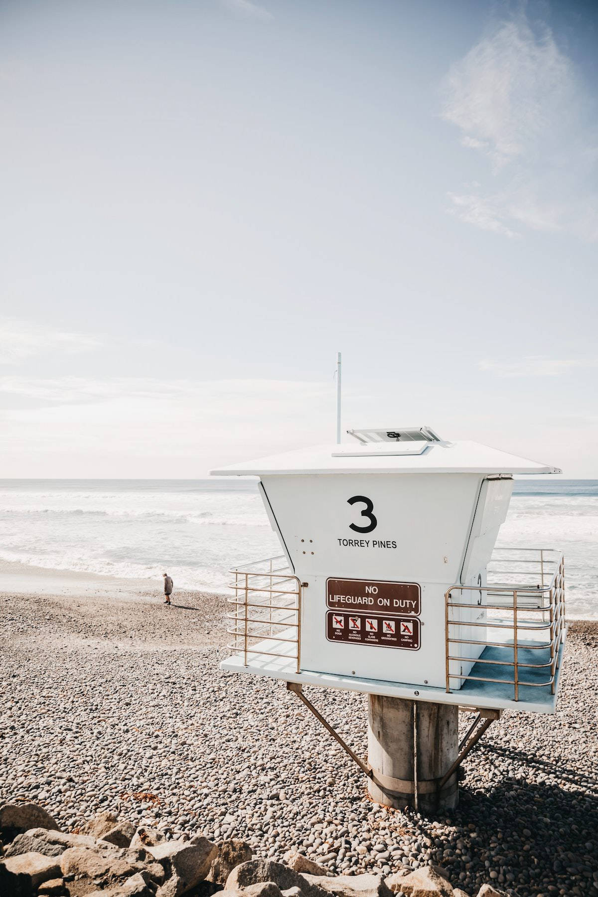 Sea 桌布 壁紙 — 一個白色救生塔標有「3 Torrey Pines」，矗立在岩石海灘上，海浪在晴朗的天空下拍打。
