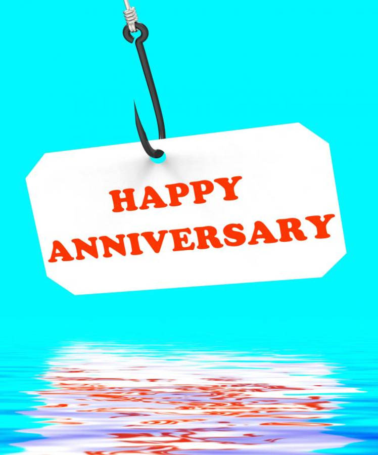 Happy Anniversary 桌布 壁紙 — 一個白色標籤，上面有紅色 'HAPPY ANNIVERSARY' 文字，掛在魚鉤上，下方是波光粼粼的藍綠色水面。