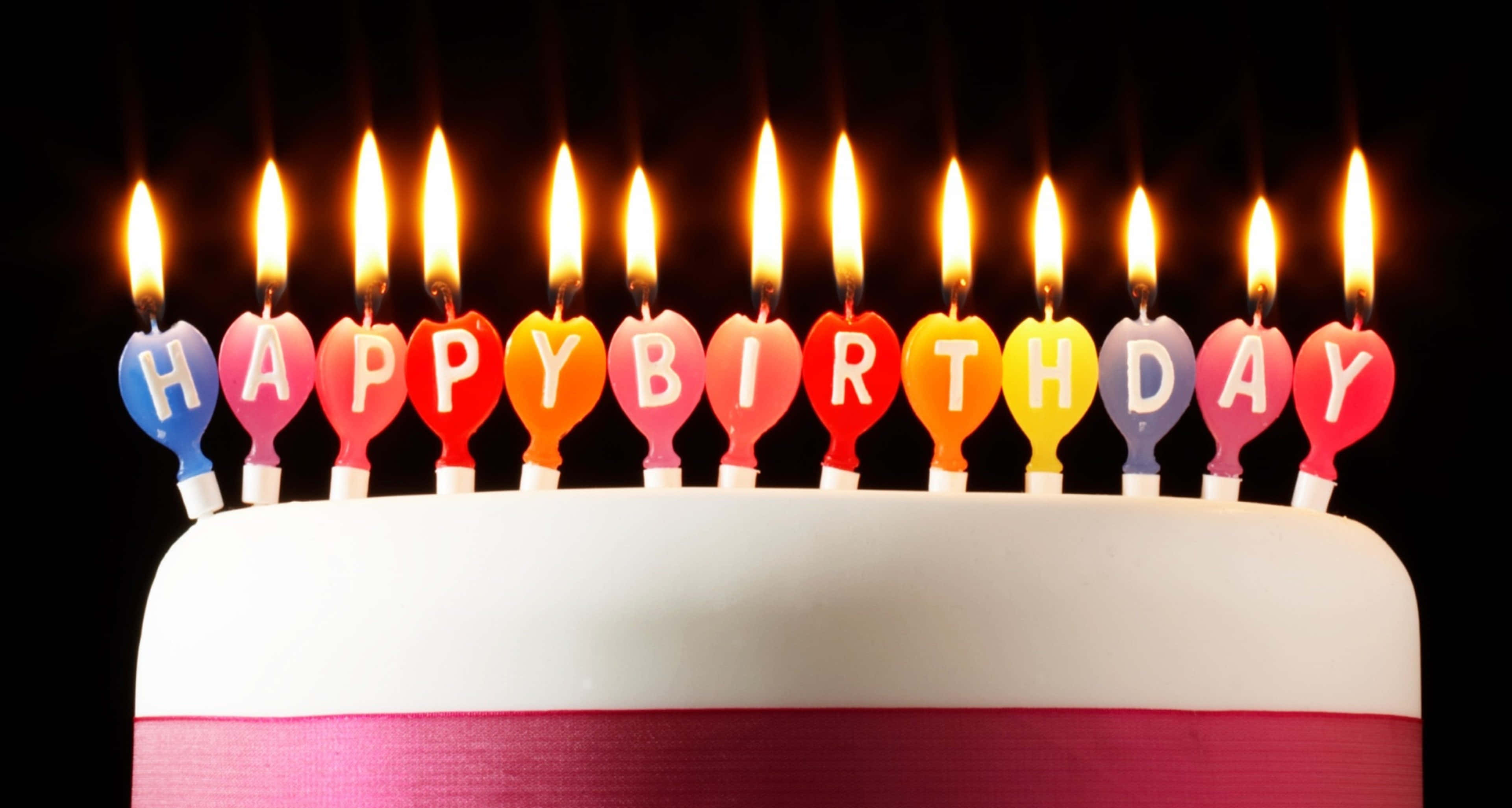 Birthday Wishes 桌布 壁紙 — 一個白色生日蛋糕，上面有彩虹色心形蠟燭，在黑色背景上拼出「HAPPY BIRTHDAY」。