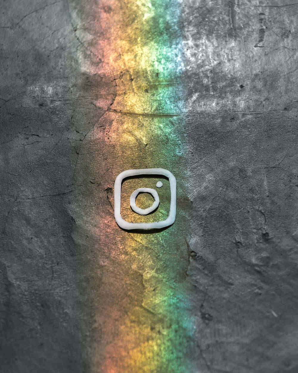 Logo Design 桌布 壁紙 — 一個白色的Instagram標誌放置在一個被鮮豔彩虹光線照亮的裂紋灰色表面上。