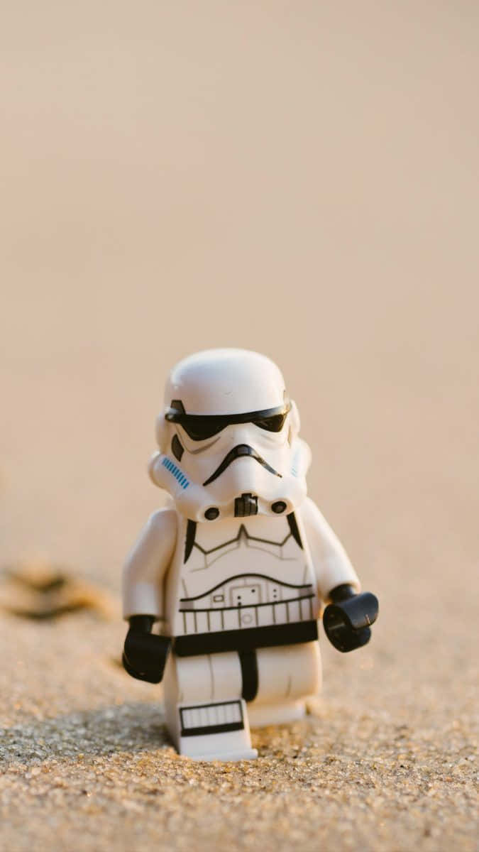 cool iPhone home screen 桌布 壁紙 — 一個白色的LEGO風暴兵獨自站在有紋理的沙地上，沐浴在溫暖的金色光線中。