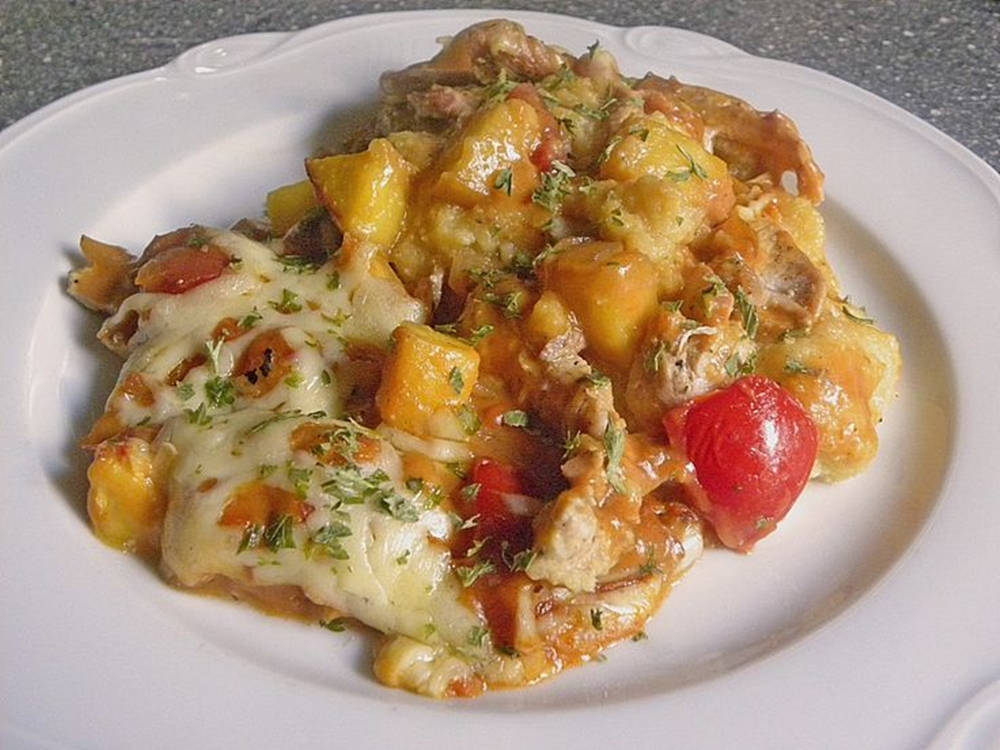 Polenta 桌布 壁紙 — 一個白色盤子上，有奶油起司焗雞肉塊和櫻桃番茄，並以新鮮香草裝飾。