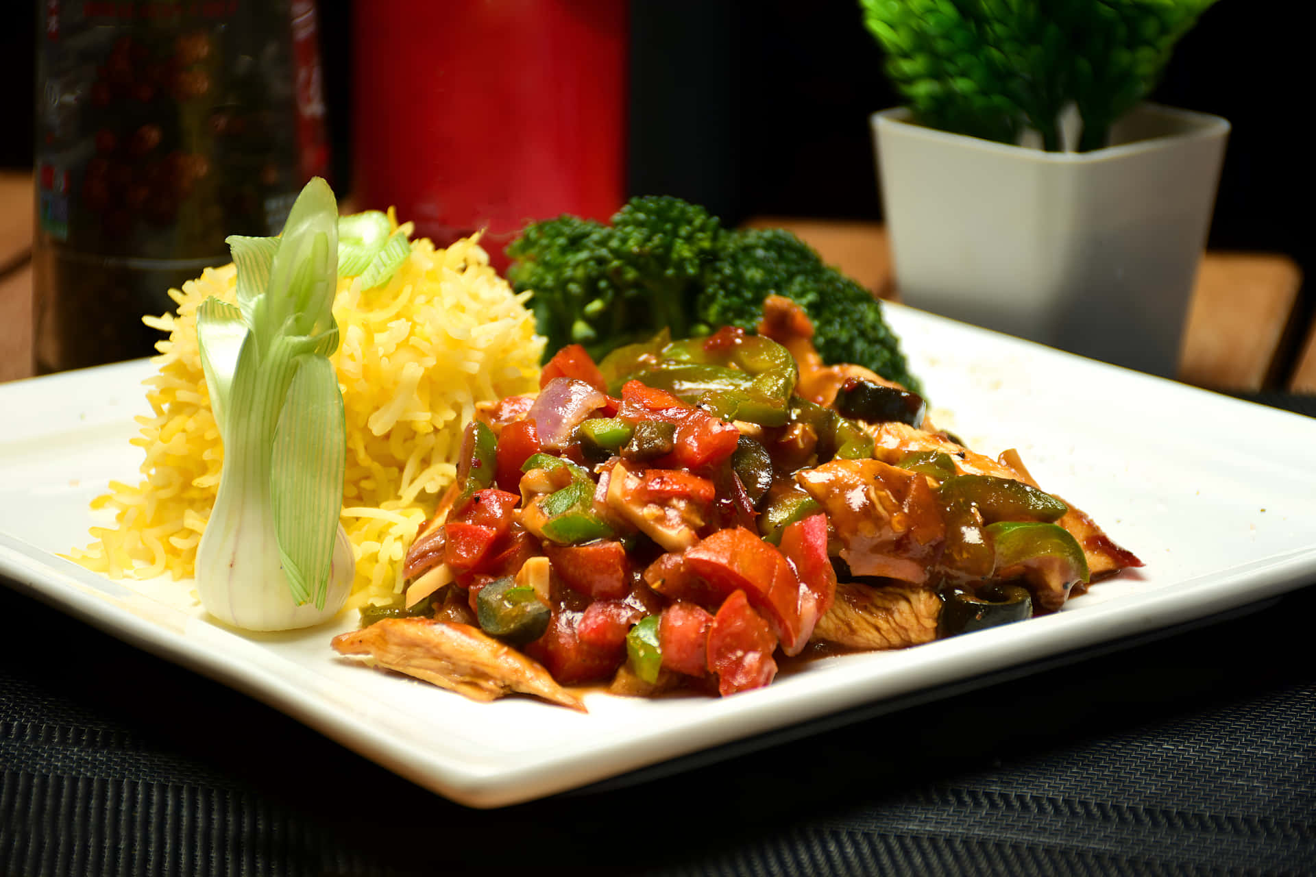 Chicken Chilli Dry with rice on a plate 壁紙 — 一個白色盤子上，有色彩繽紛的雞肉、甜椒和洋蔥炒菜，配上黃飯和青花菜。