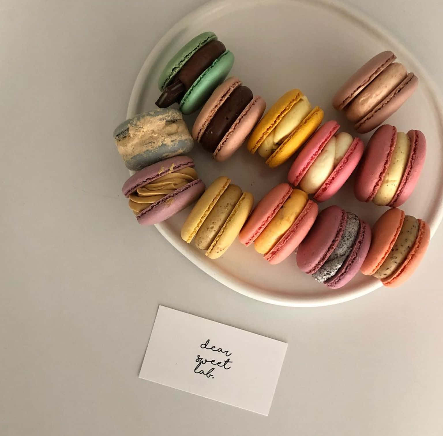 french 桌布 壁紙 — 一個白色盤子上放著色彩繽紛的馬卡龍，排列成半圓形，還有一張手寫便條寫著 dear sweet lab。