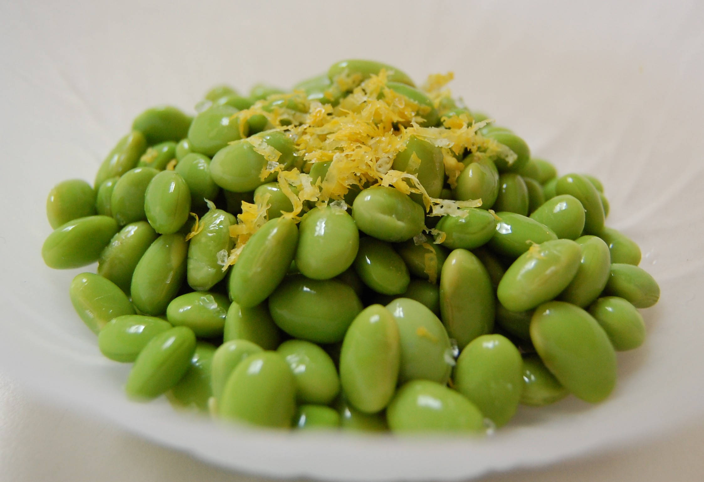 Vegetables 桌布 壁紙 — 一個白色碗中，鮮綠色毛豆配上亮黃色檸檬皮的近距離特寫。