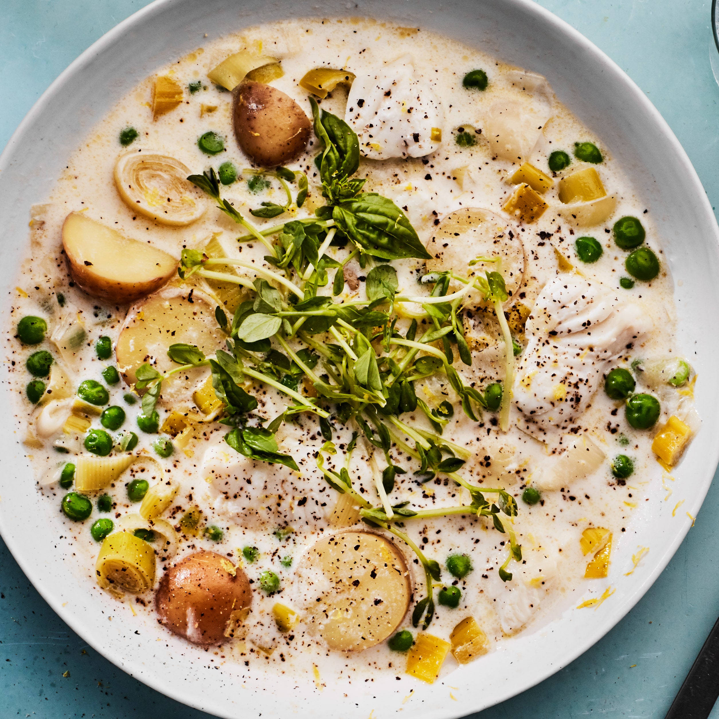Chowder 桌布 壁紙 — 一個白色碗中的奶油白魚燉菜，上面放有新鮮的微型蔬菜、豌豆、馬鈴薯和檸檬。