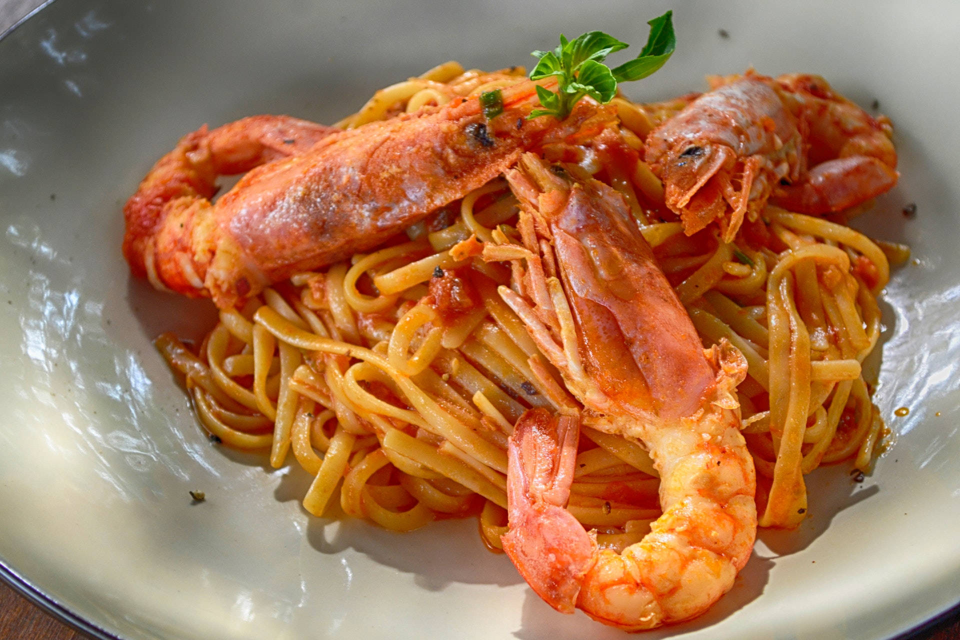 Food Photography 桌布 壁紙 — 一個白色碗的特寫，裡面裝滿了番茄醬義大利麵，上面放著大隻熟蝦和新鮮羅勒。