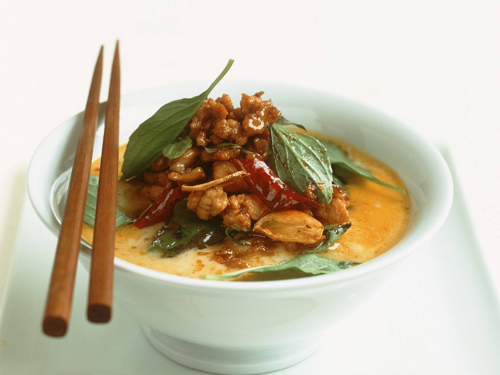 Delicious Food 桌布 壁紙 — 一個白色碗盛著奶油黃咖哩，上面放有絞肉、紅辣椒和新鮮羅勒葉，旁邊放有木筷子。