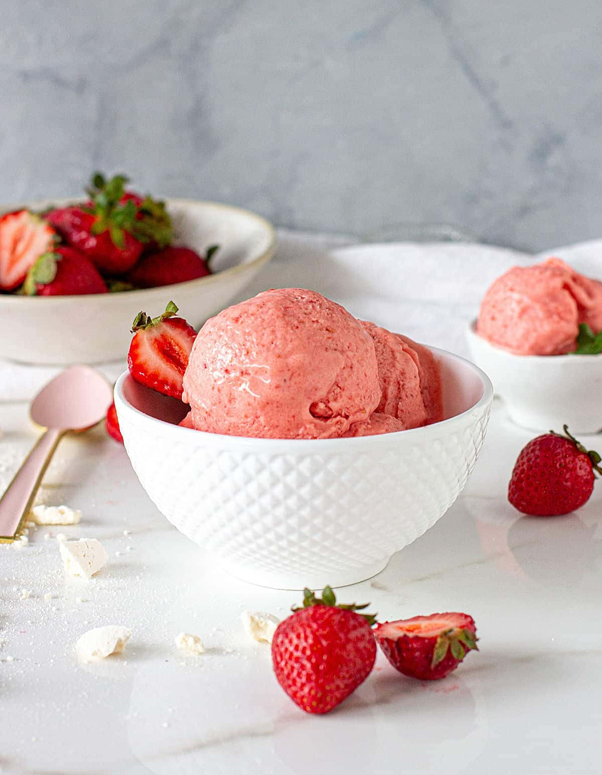 Strawberries 桌布 壁紙 — 一個白色碗盛裝著鮮豔粉紅色的草莓冰淇淋，周圍是新鮮完整和切片草莓，放在大理石表面上。
