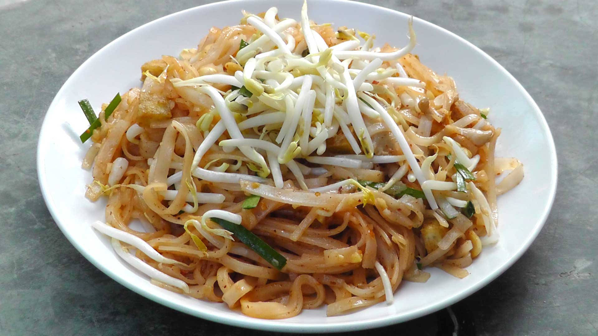 thai 桌布 壁紙 — 一個白色碗裝滿炒米粉，上面放上新鮮豆芽和切碎的青蔥。
