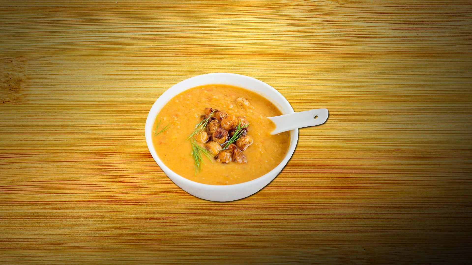 Soup 桌布 壁紙 — 一個白色碗裝著奶油橙色湯，上面放有烤鷹嘴豆和新鮮蒔蘿，放在溫暖的木質表面上。
