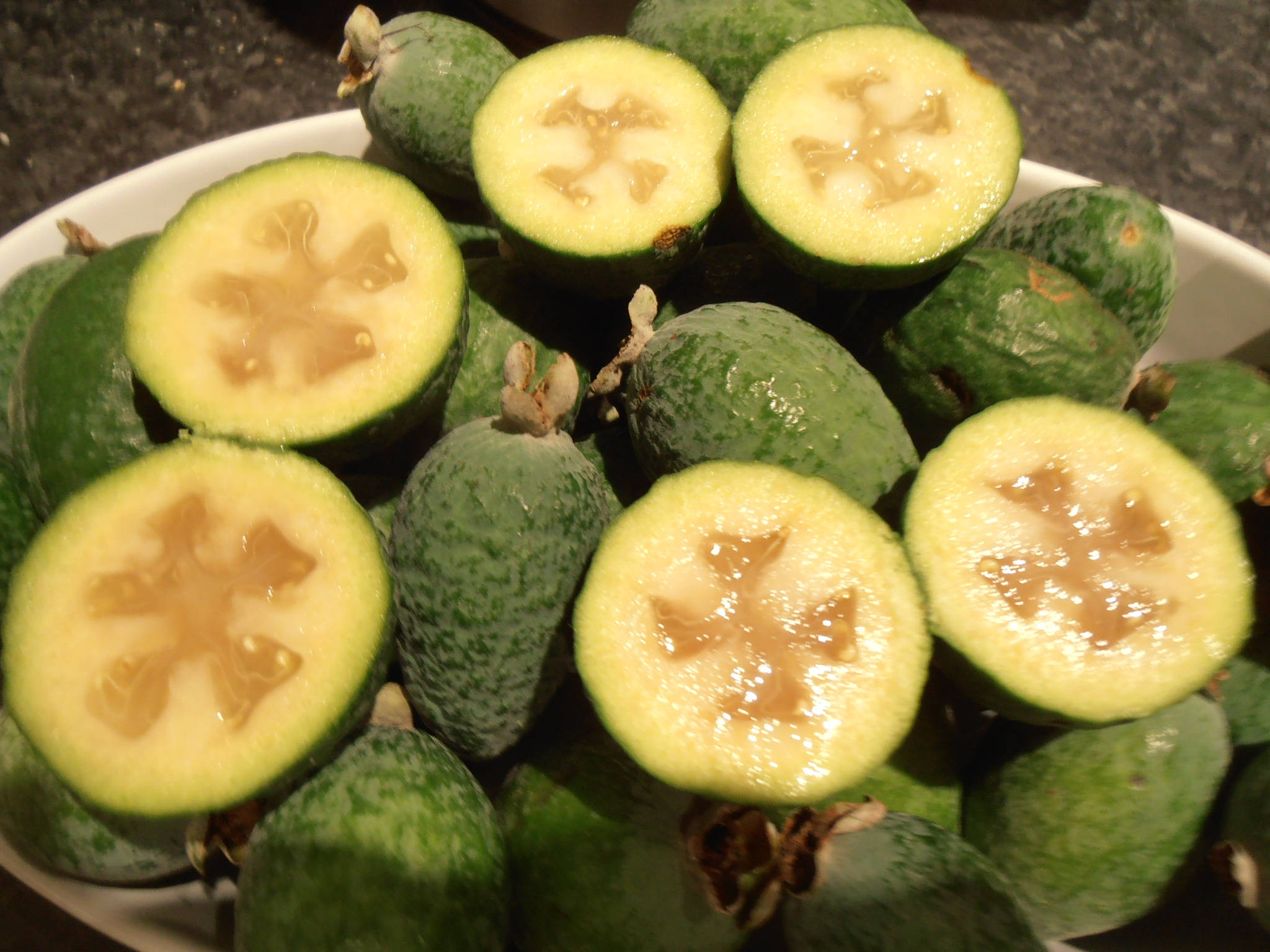 Fruit 桌布 壁紙 — 一個白色碗裝著新鮮的綠色菲油果，有些切開露出星形淡黃色內部。