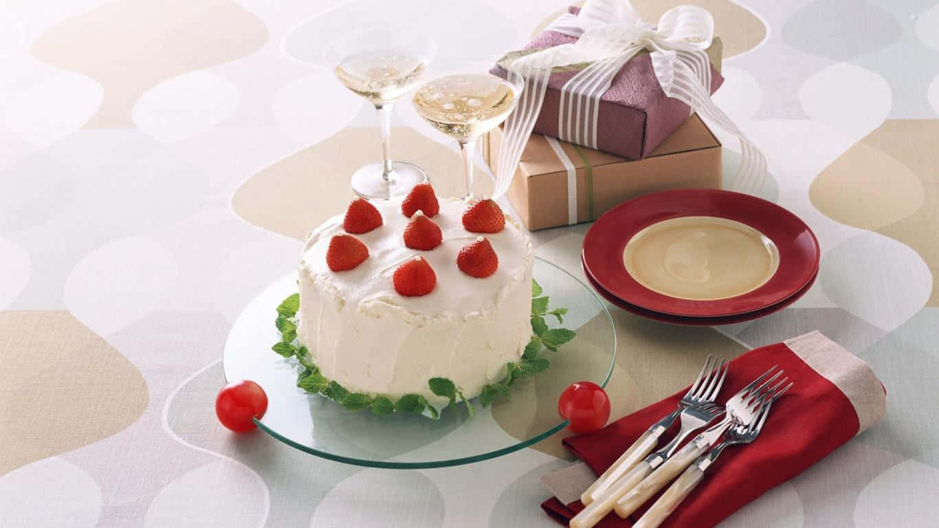 1366x768 Desserts 桌布 壁紙 — 一個白色糖霜蛋糕，上面放有新鮮草莓，放在玻璃盤上，旁邊有香檳杯和包裝好的禮物，置於圖案桌布上。