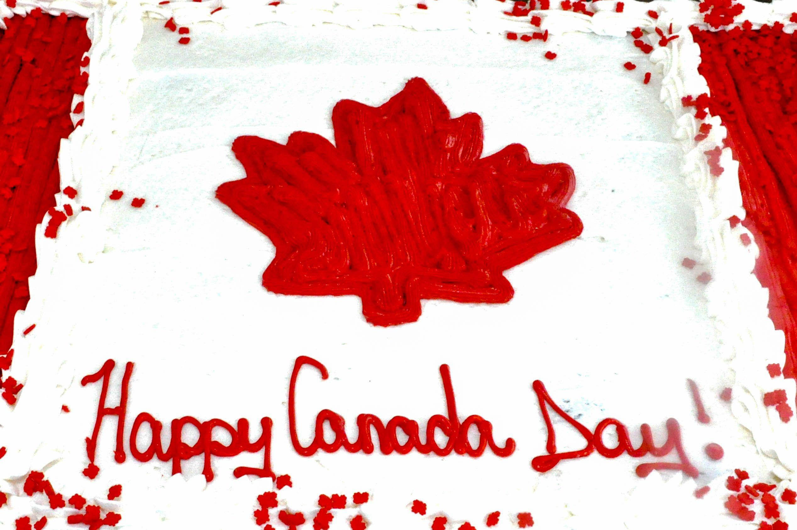 Canada Day 桌布 壁紙 — 一個白色糖霜蛋糕，裝飾著紅色楓葉和紅色糖霜字樣「Happy Canada Day」，周圍撒滿紅色糖粒。