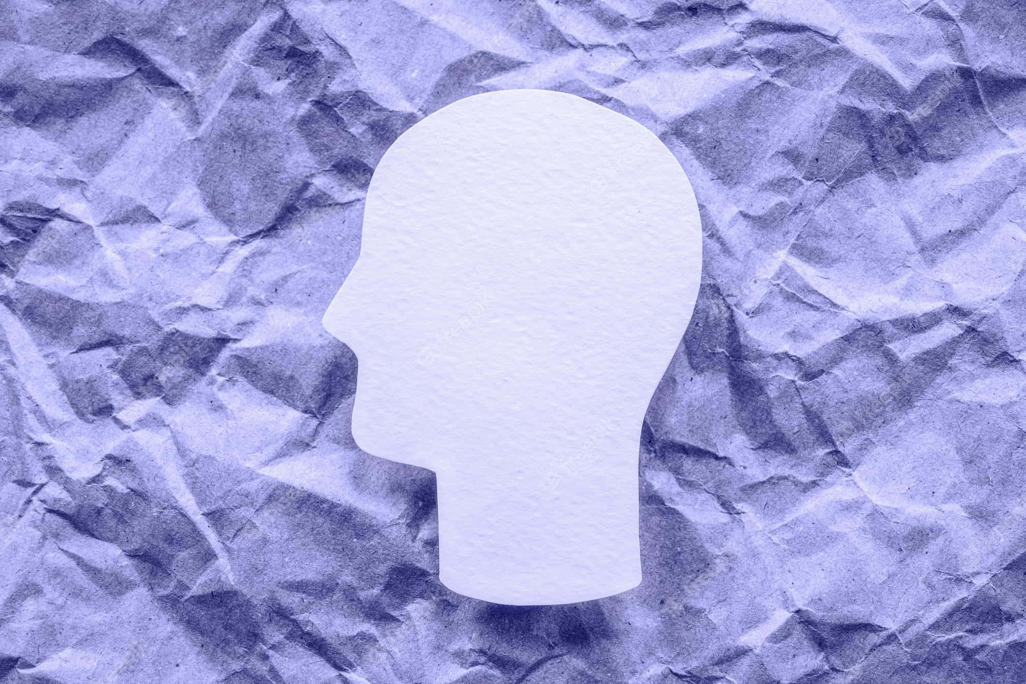 Psychology 桌布 壁紙 — 一個白色紙剪出的人類頭部剪影放在有紋理的紫色皺紙上。