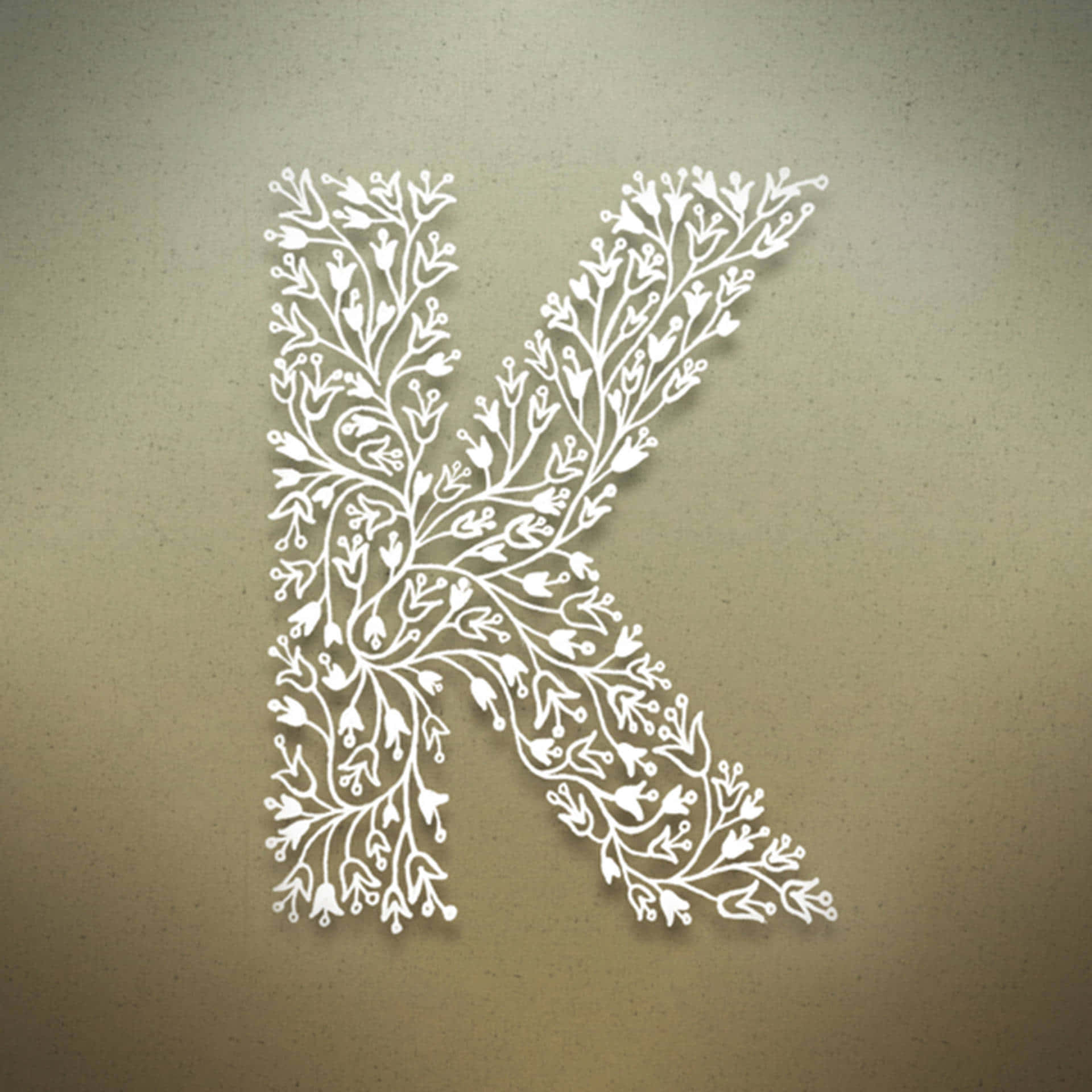 K 桌布 壁紙 — 一個白色紙雕字母K，飾以精緻花卉圖案，背景為有紋理的米色。