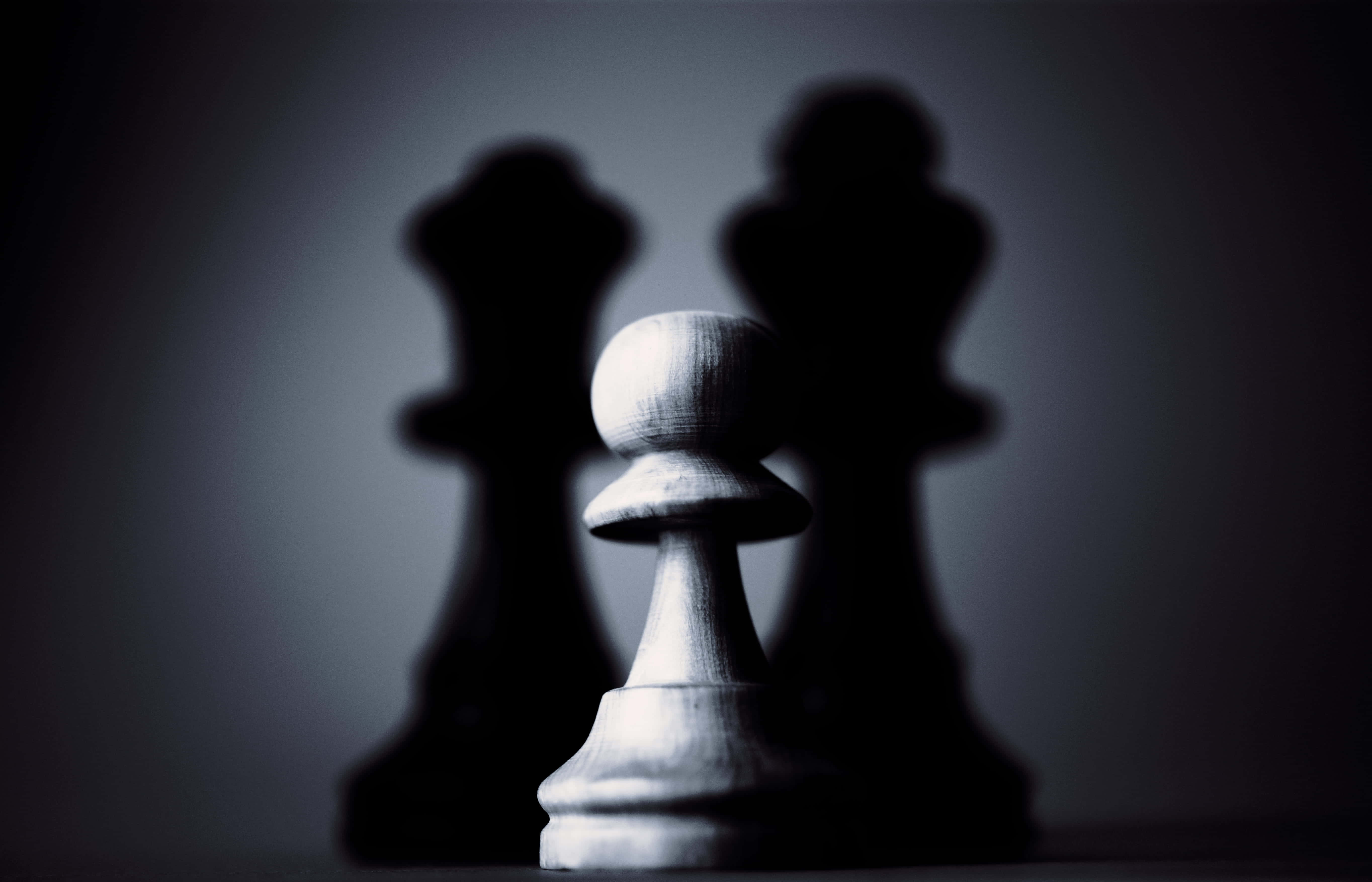 shadow 桌布 壁紙 — 一個白色西洋棋兵在黑暗漸變背景上，對著模糊的黑色國王剪影，清晰對焦。
