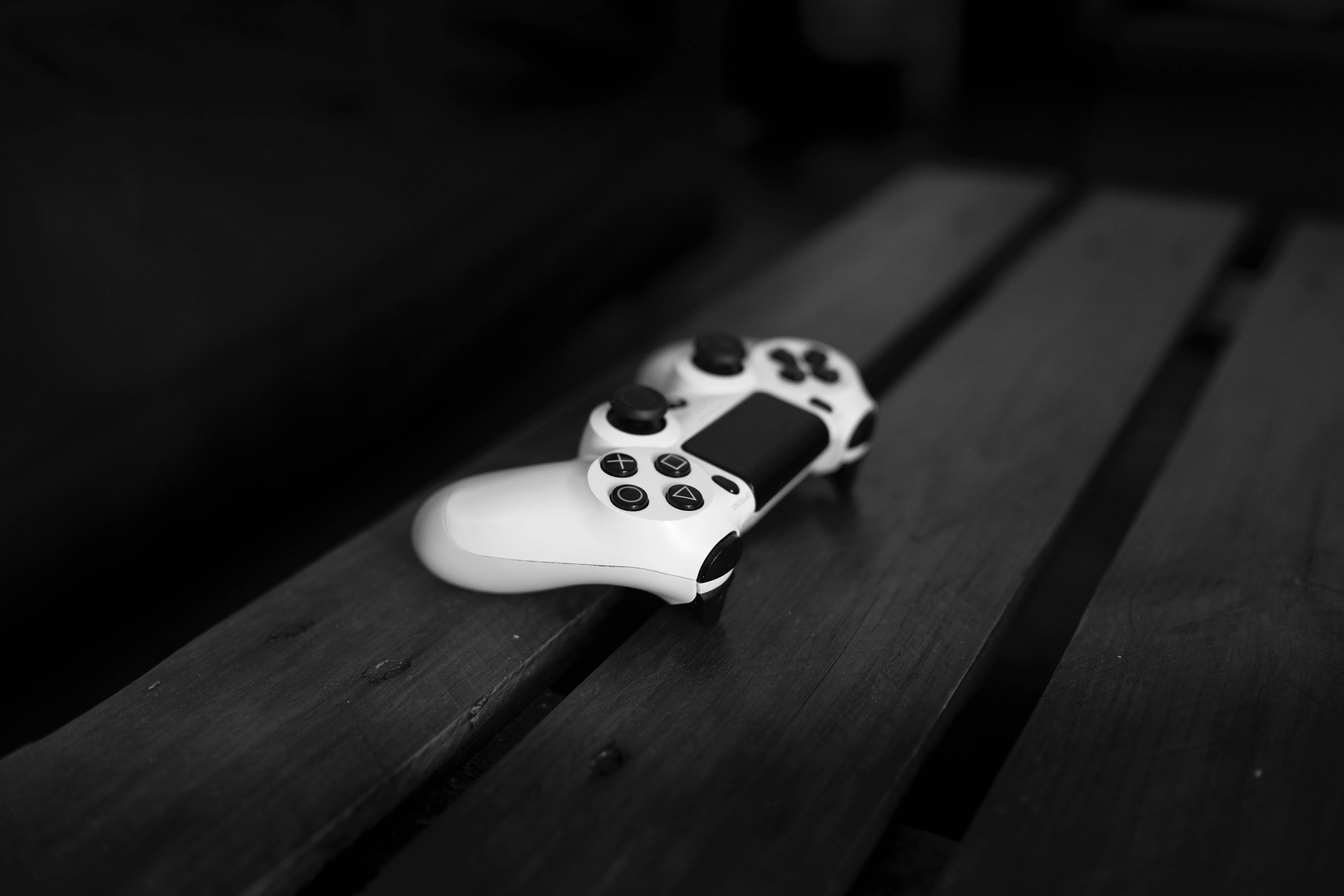 Dim 桌布 壁紙 — 一個白色遊戲手把放在深色木條上，構成鮮明的黑白構圖。