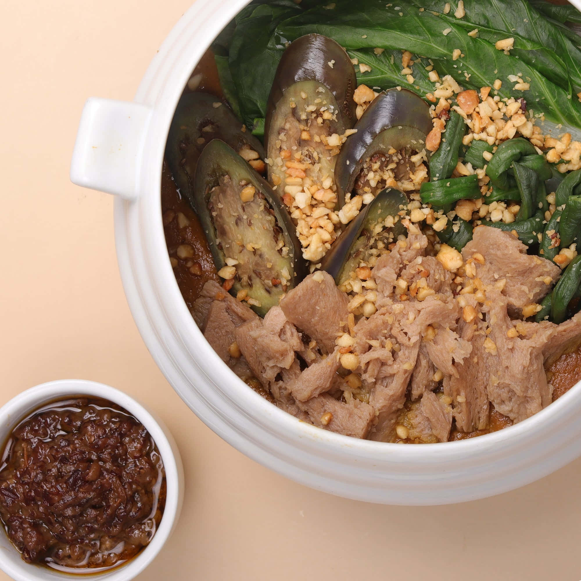 Vegetables 桌布 壁紙 — 一個白色陶瓷碗，裝滿嫩肉片、茄子和菠菜，上面撒上碎花生，旁邊配有深色蘸醬。