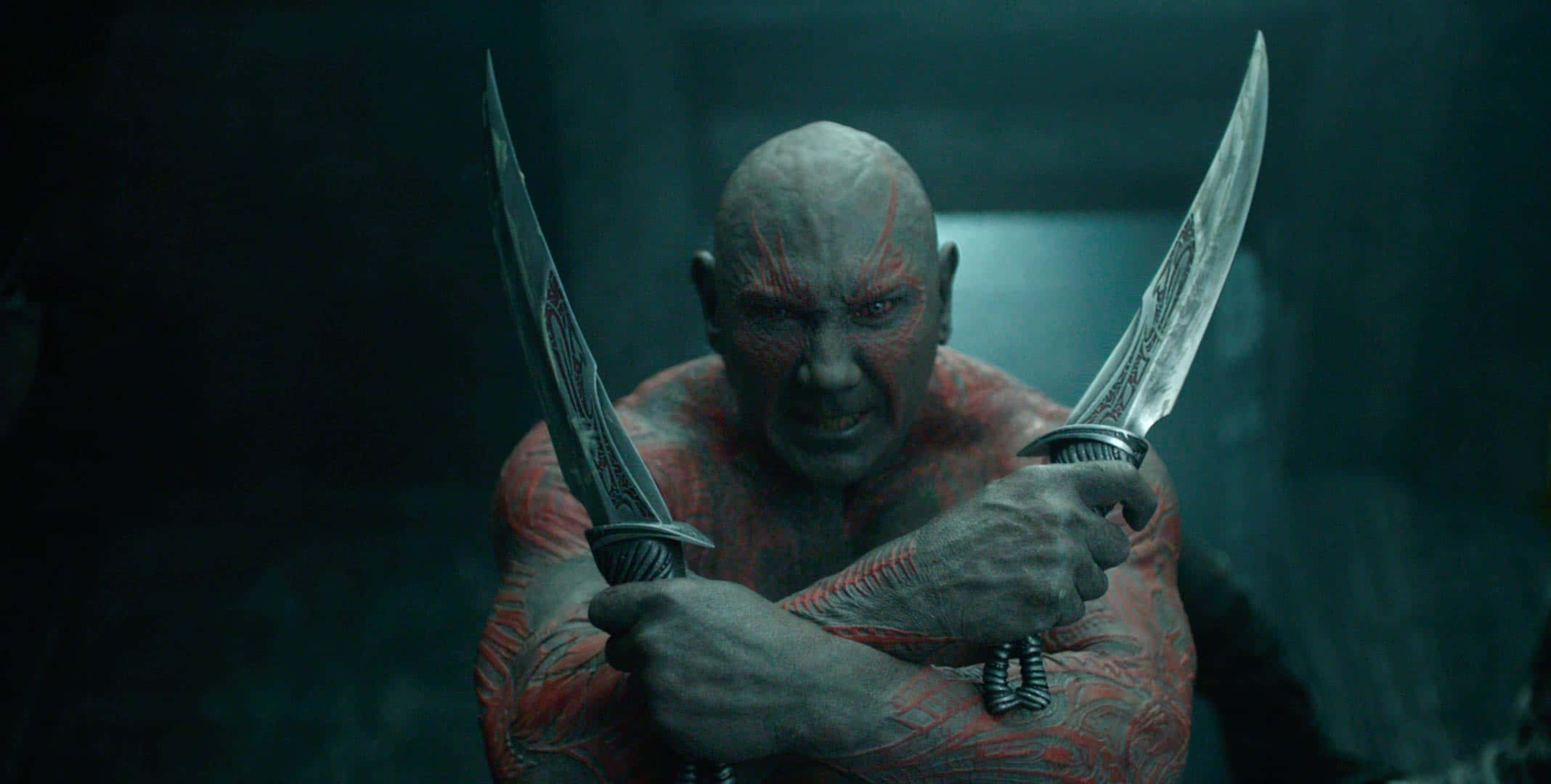 Guardians Of The Galaxy 2 桌布 壁紙 — 一個皮膚血紅、眼神發光的兇猛戰士，在昏暗陰沉的環境中緊握兩把華麗的刀刃。