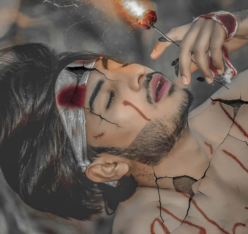 Broken 桌布 壁紙 — 一個皮膚龜裂、帶有血痕的男人躺著，一隻手拿著一朵燃燒的玫瑰舉在他的臉上，構成超現實的數位場景。