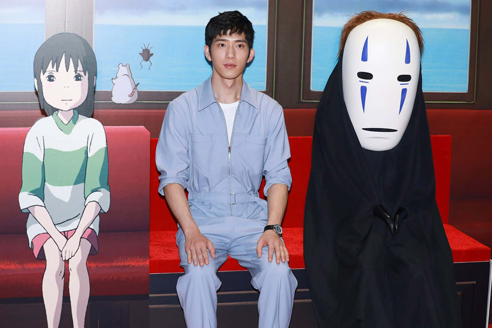 吉卜力工作室 桌布 壁紙 — 一個真男人坐在紅色沙發上，兩邊是《神隱少女》的兩個動畫角色。