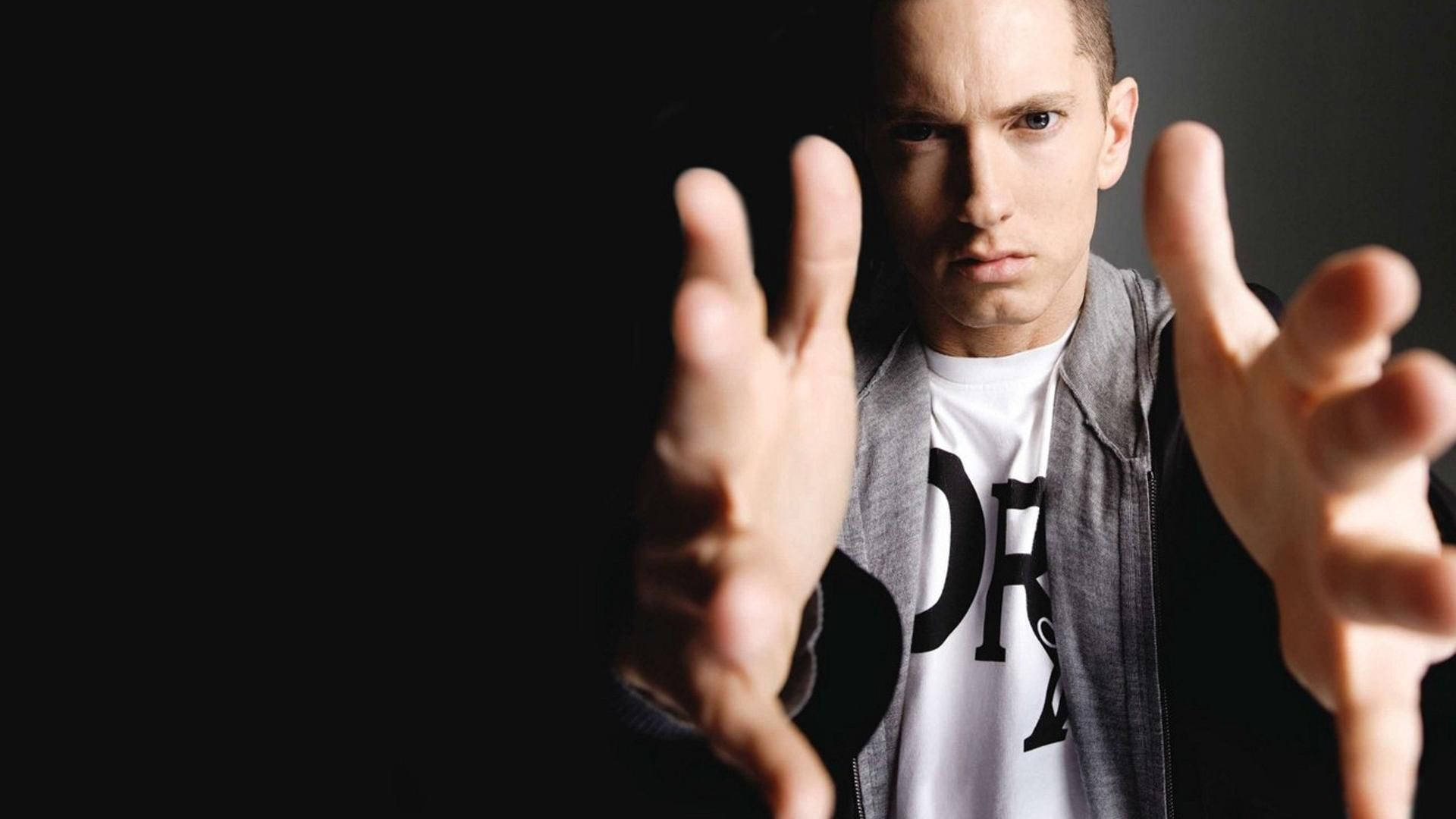 Eminem 桌布 壁紙 — 一個眼神銳利、雙手伸出的男人，在純黑背景下直視觀眾。