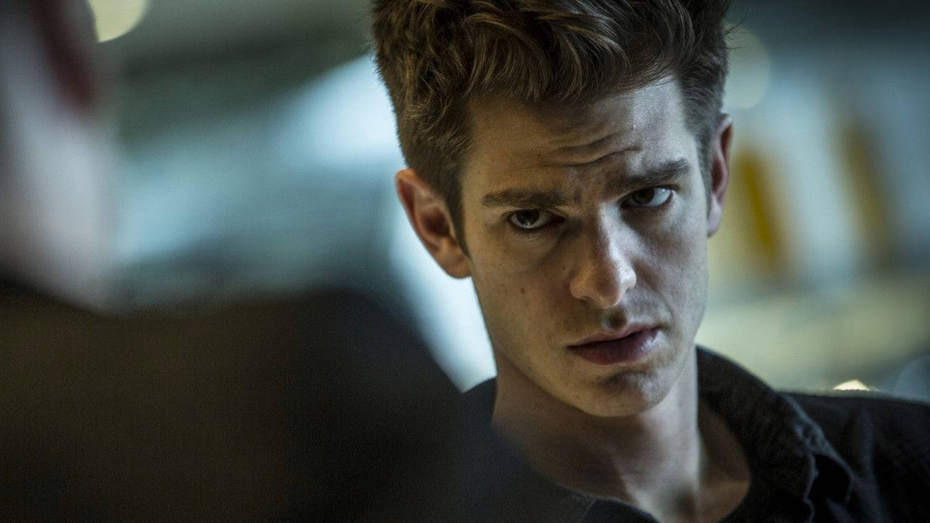 Peter Parker 桌布 壁紙 — 一個眼神銳利、頭髮凌亂的男人在昏暗的室內環境中專注地凝視。