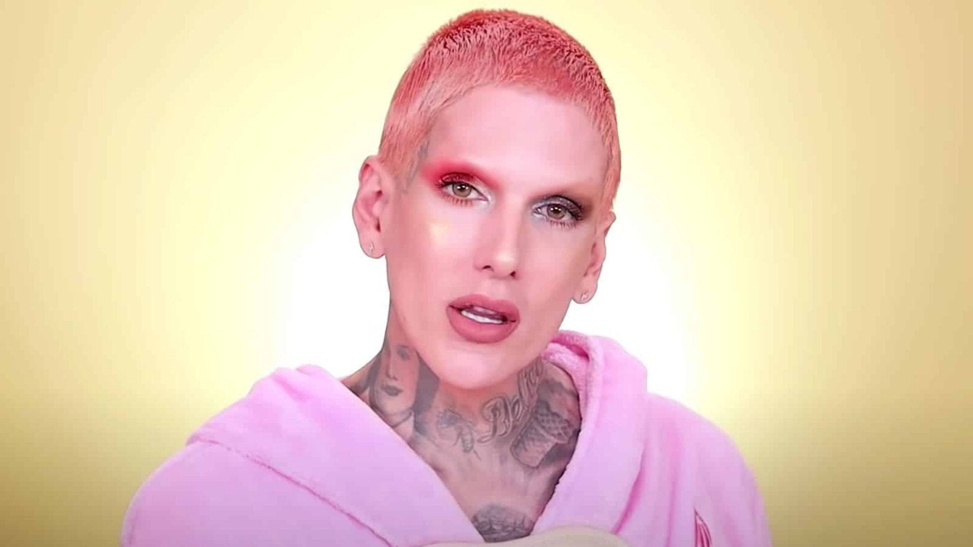 Jeffree Star 桌布 壁紙 — 一個短粉紅頭髮和刺青的人，穿著粉紅色連帽衫，背景是柔和的黃色漸層。