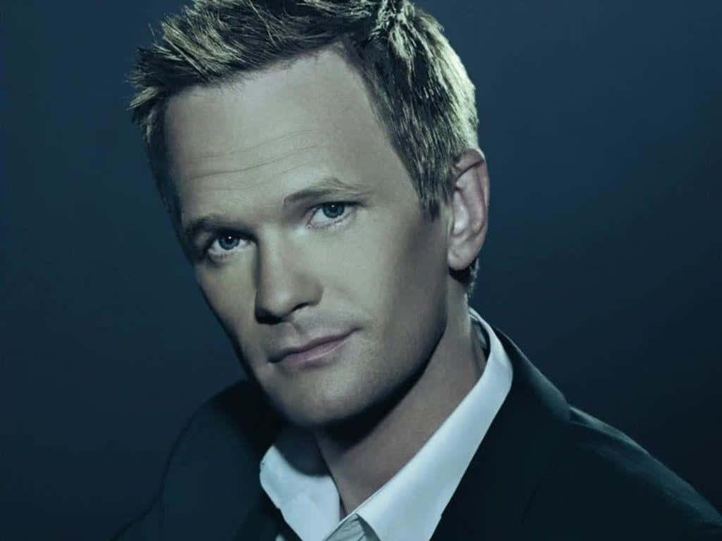 neil patrick harris 桌布 壁紙 — 一個短金髮男人的特寫肖像，穿著深色西裝和白色襯衫，背景是深藍色。